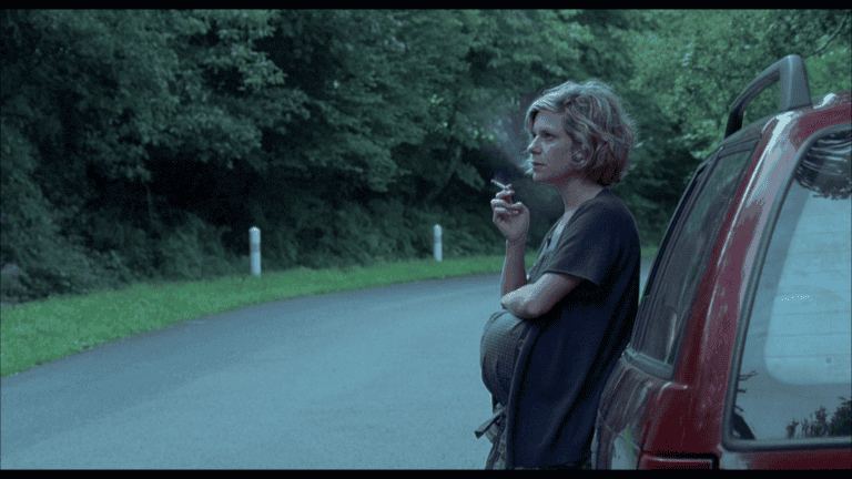 scene from the movie making plans for lena, uma mulher grávida encostada num carro e fumando.